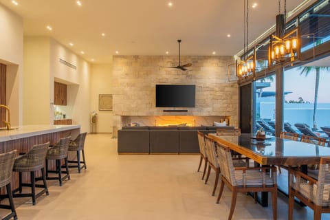 Relax in your elegant open-plan living space with stone fireplace, modern kitchen, and oceanview dining for unforgettable vacation moments.