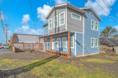 A charming two-story coastal rental featuring bright blue siding and orange trim details in a quiet residential setting.