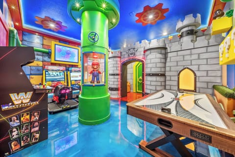 Step into a lively game room adorned with colorful murals and cheerful decor. The shiny blue floor reflects playful lights, while arcade machines and a unique air hockey table promise endless fun and friendly competition.