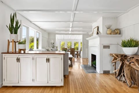 The coastal vibes in this home are next level. Walk through the living area to the dining area with seagrass chairs. The living room has a smart TV, the fireplace is inoperable. 