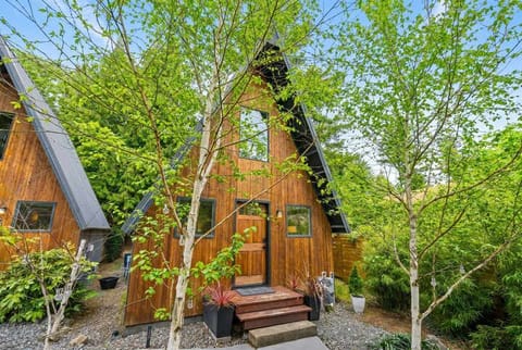 Framed by fresh spring greenery — your A-frame sits beautifully among the trees, equal parts cozy retreat and natural escape.