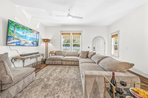 Bright and airy living room with soaring ceilings, ceiling fan, smart TV, and the signature arched doorway that runs throughout this gorgeous brand-new Seminole Heights home. Light pours in from every angle.