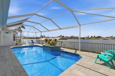 Heated pool and spa on the paver deck with tropical landscaping and the canal waterway visible in the background