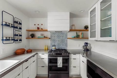 Fully stocked chef’s kitchen featuring custom open shelving, artisan tile backsplash, and modern appliances. Enjoy cooking with ease - from morning coffee to family dinners. Everything you need to feel right at home in Austin.
