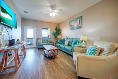 Cozy coastal living room with plush seating, big-screen TV, and balcony access.