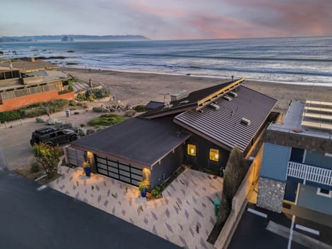 An elevated dusk view of the modern beachfront home with a view of the shoreline.