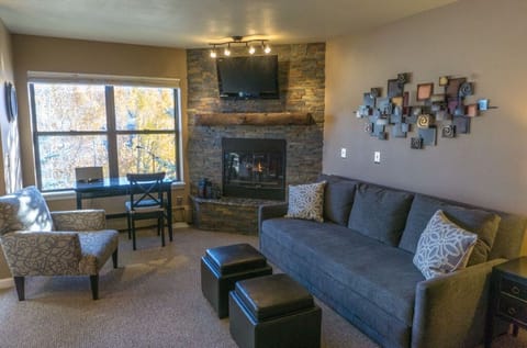 Relax in the cozy living room featuring a comfortable sofa, a flat-screen TV, and a warm fireplace for chilly nights.