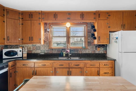Step into your fully equipped kitchen featuring warm wood cabinetry, decorative tile backsplash, and everything you need for home-cooked meals.