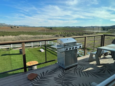 Deck with BBQ and two picnic tables looking over yard game area with great views