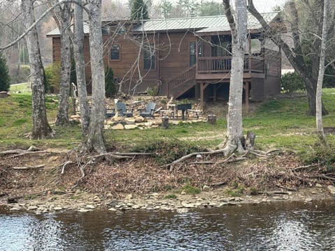 Front of cabin with fire pit from across the river