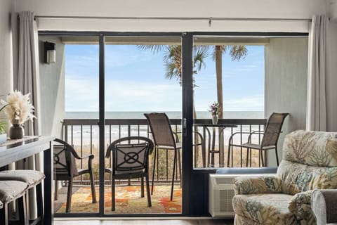 Floor-to-ceiling windows open onto the balcony in this oceanfront living room at Savoy at Grande Cayman.