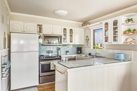 Your fully equipped kitchen features white cabinets, stainless appliances, and charming blue subway tile backsplash for delightful home cooking.