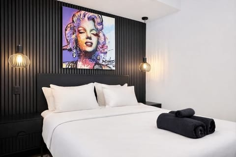 Centré au-dessus du lit, le portrait de Marilyn Monroe aux teintes lavande néon et bleu électrique brise le monochrome. C'est l'élément "punchy" qui donne toute son âme à la pièce.