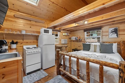 Cozy studio layout featuring a queen bed, full kitchen, and warm log cabin details all in one comfortable space.