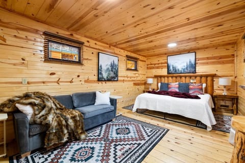 Warm wood cabin charm with a comfy bed, soft linens, and a lounge sofa for relaxing after a day in the Black Hills.