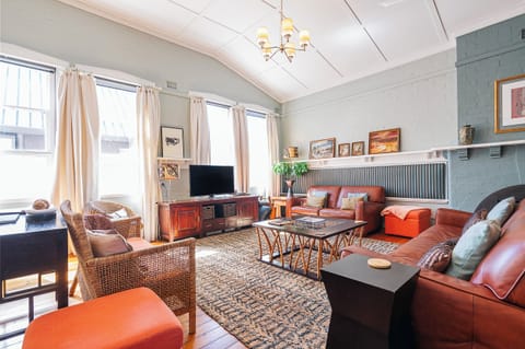 Unwind beneath high ceilings where timber floors, layered rugs and soft lighting frame evenings by the gas fire or slow mornings with coffee on the sofa.