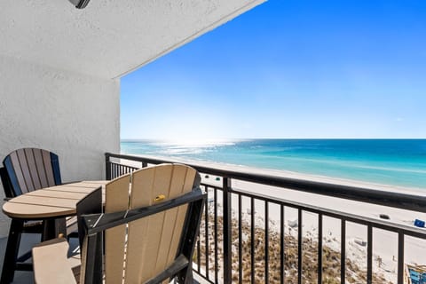 The balcony overlooks the turquoise waters of the Gulf and the sugar‑white sands of the beach below.