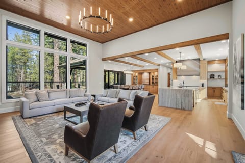 Unwind in this stunning open-concept living space where soaring wood ceilings and floor-to-ceiling windows frame forest views perfectly.