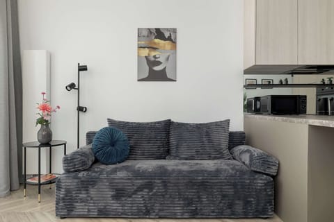 A modern living room with a gray sofa and decorative pillows. Minimal wall art and soft lighting create a calm atmosphere. The space feels tidy and inviting.