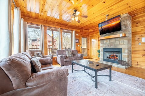 Cozy up in your rustic living room with plush leather seating, crackling fireplace, and mountain views through floor-to-ceiling windows.