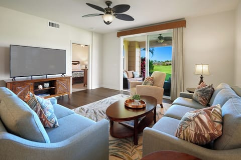 Relax in your spacious living room with plush seating, entertainment center, and stunning golf course views through sliding glass doors.