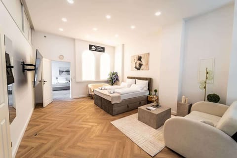 Stylisches Zimmer mit 2 Couches, Queen-Size Schlafbett und 65-Zoll-SmartTV.
