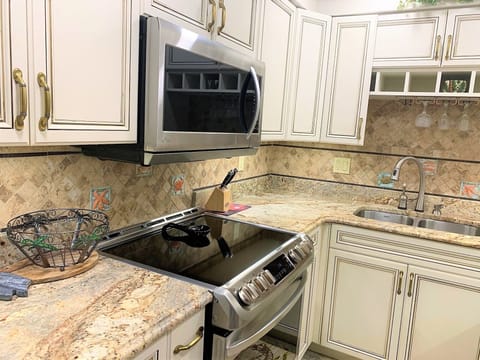 Your elegant kitchen awaits with granite countertops, premium appliances, and golden touches creating a warm culinary haven.