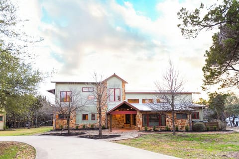 Modern vacation home with stone and wood accents, featuring spacious grounds and mature trees in a peaceful setting.