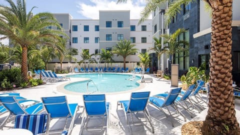 Bask in the sun by the sparkling pool, surrounded by swaying palm trees and comfortable lounge chairs.