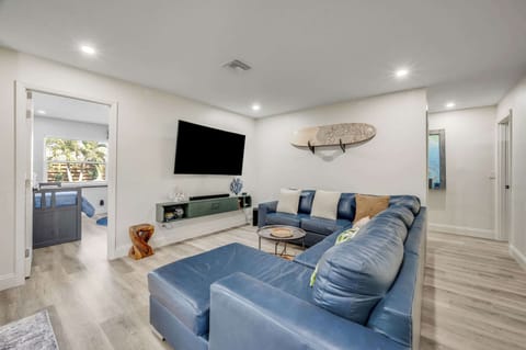 Relax in the modern living room featuring a large blue sectional and wall-mounted television.