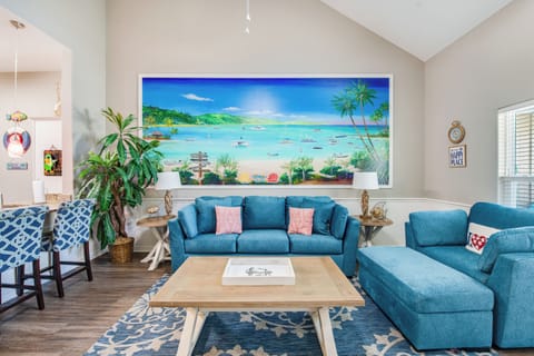 Sink into plush blue seating as tropical artwork transports you to paradise, while coastal-inspired decor creates your perfect beach house retreat.