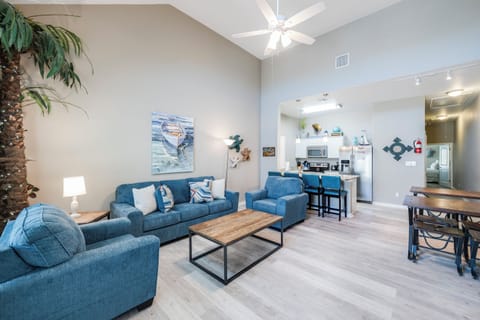 Relax in your bright, open-concept living space with soaring ceilings, coastal artwork, and modern kitchen with breakfast bar seating.