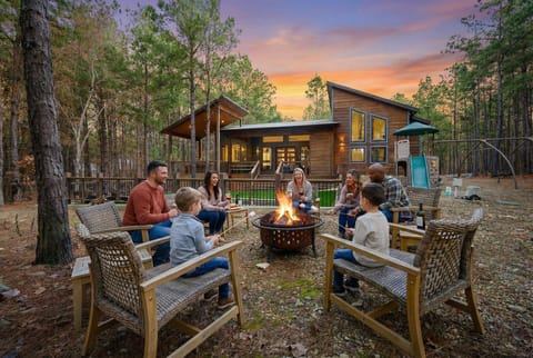 Modern woodland cabin with fire pit, deck, and kid-friendly play area.