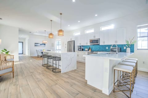 Modern, luxurious kitchen with plenty of counter space and seating, flowing into a bright open-concept dining area.