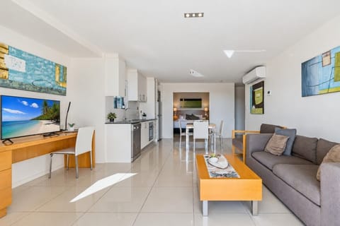 A bright, open-plan living area with a fully equipped kitchen, smart TV, and study desk — comfortable and ready for a longer stay.