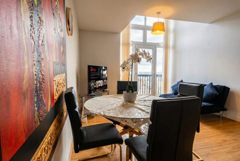 Bold artwork, dining for four and a sunlit balcony view share one bright open space.