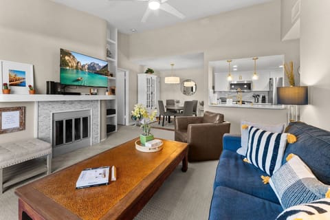 A bright, open-concept room seamlessly integrates the fully cozy living room area with a flat screen TV flowing into a modern dining area and kitchen