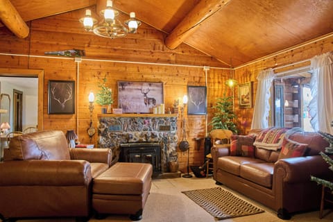 Centered view of the rustic living room's leather seating and stone fireplace.