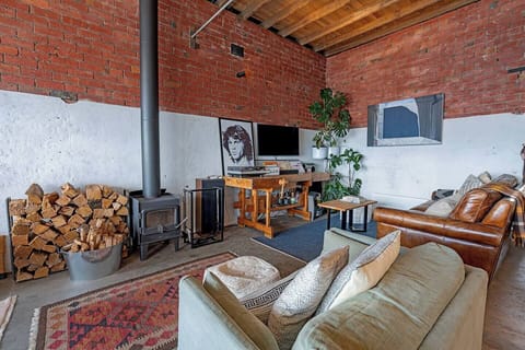 Unwind in the industrial-style living area, where plush seating, a record player and TV sit beside the crackling wood fireplace, creating the perfect setting for cosy evenings in.