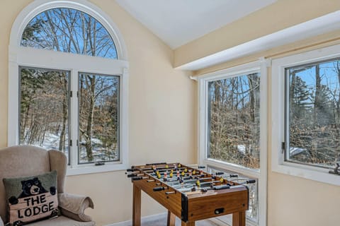 Sun room with foosball table, wingback chair, and arched window