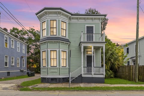 The mint green exterior of Mint Julep glows beautifully at sunset, showcasing the home's classic Victorian charm.