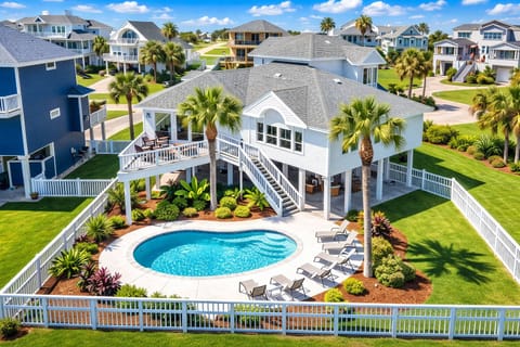 Luxury beachfront vacation home in Galveston with resort-style private pool, palm trees, and spacious outdoor lounging area – perfect coastal getaway in Rum Bay.