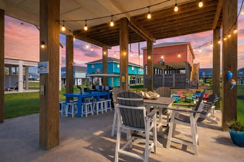 Large covered outdoor entertaining area with dining tables and seating under the home, ideal for relaxing after a day at the beach in Galveston.