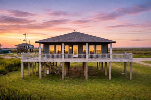 Beachfront stilt home with panoramic ocean views at sunrise in Bolivar Peninsula, TX, featuring elevated deck, coastal design, and direct beach access.