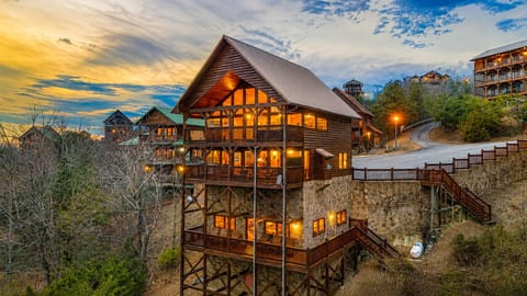 Large luxury cabin exterior with illuminated decks, mountain surroundings, and spacious accommodations in Sevierville, Tennessee.