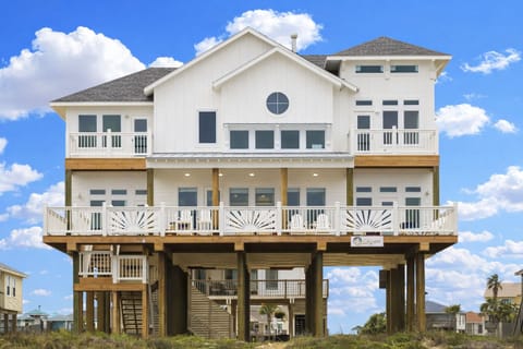 Stunning Gulf-front beach house exterior with elevated design, private parking, and expansive balconies overlooking the ocean.