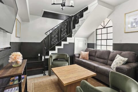 Inviting living room featuring comfortable seating, a Smart TV, and a striking staircase with wrought-iron details—an ideal space to relax, gather, or plan your next New Orleans adventure.
