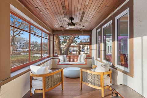 Unwind in your enclosed sun porch with panoramic windows, ceiling fan, and comfortable seating overlooking peaceful surroundings.