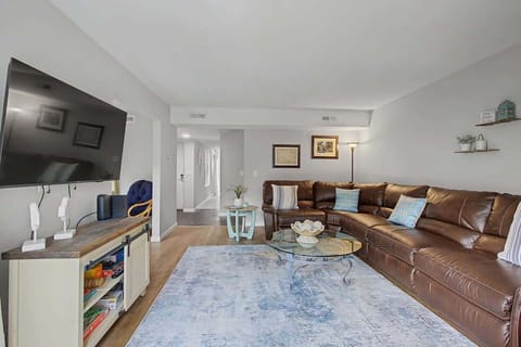 Spacious living room with a large leather sectional and mounted flat-screen television