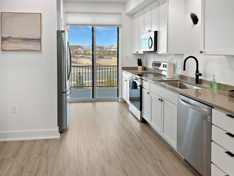 Your bright kitchen features stainless steel appliances and gleaming counters, with balcony doors opening to views of the surrounding cityscape.